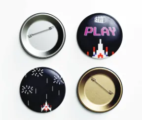 Four round badges with the pixel spaceship, PLAY lettering and starburst motifs