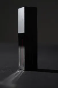 A dark perfume bottle on a reflective surface